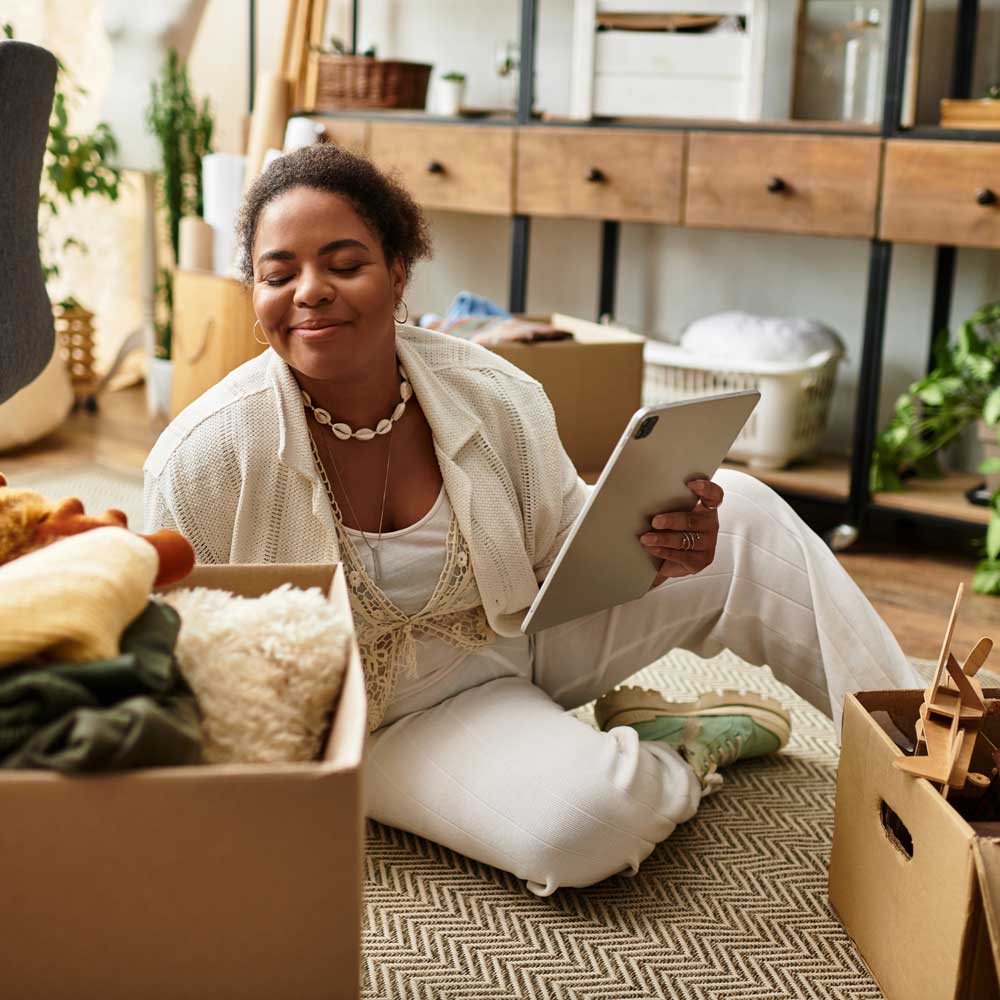 Engaging in a crafting project, a woman smiles while surrounded by organized supplies and boxes.